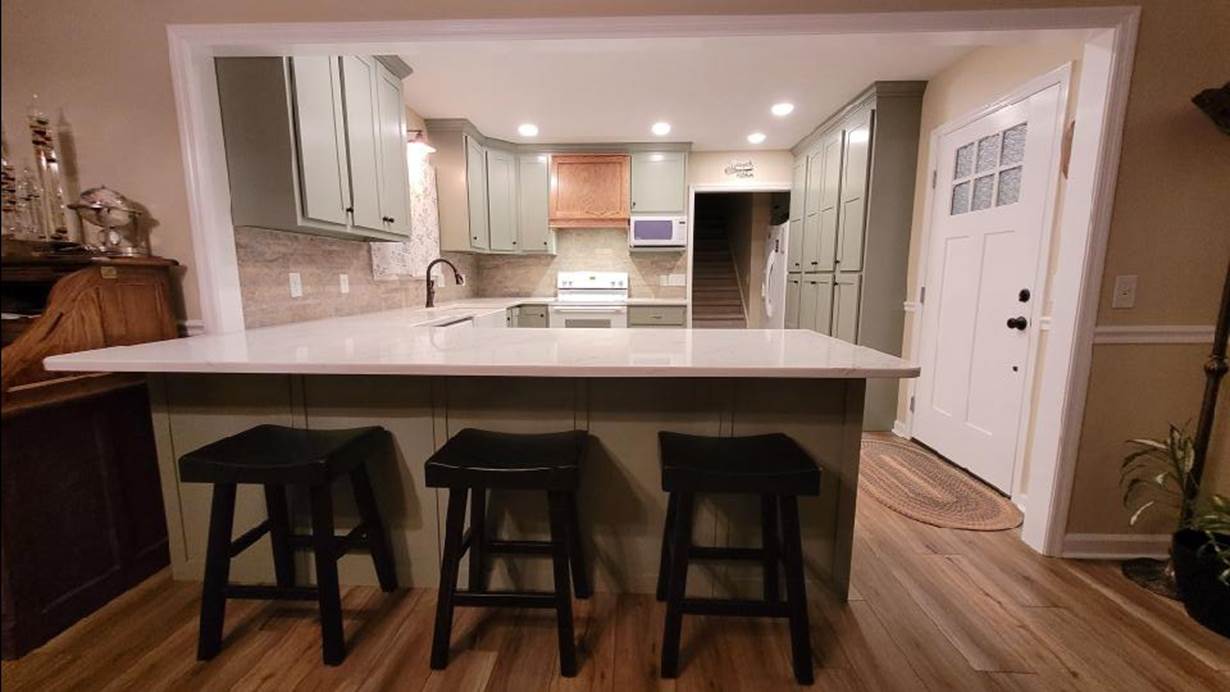 A kitchen with a bar and stools

Description automatically generated